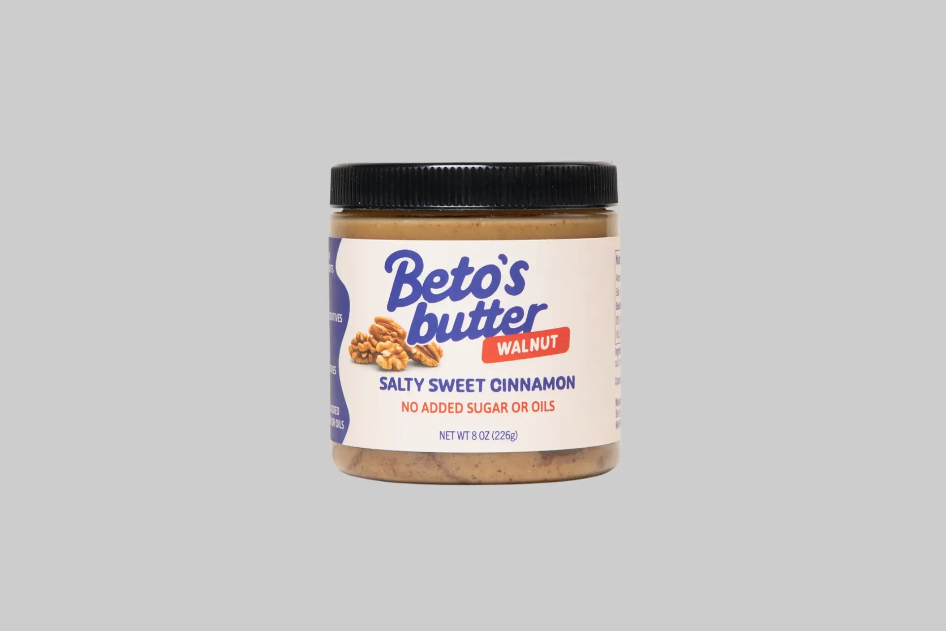 A jar of Beto's Butter Salty Sweet Cinnamon Walnut Butter with walnuts scattered around it on a light background, showing the clean label design and deep brown nut butter visible through the jar.
