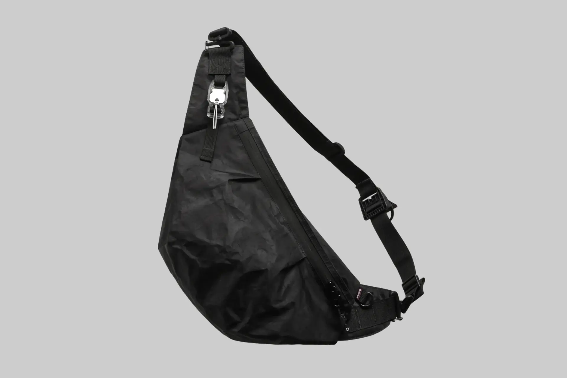 The DSPTCH Unit Sling Bag RND Edition in black Dyneema, shown being worn across the body with its sleek, minimalist design prominent. - Product Review