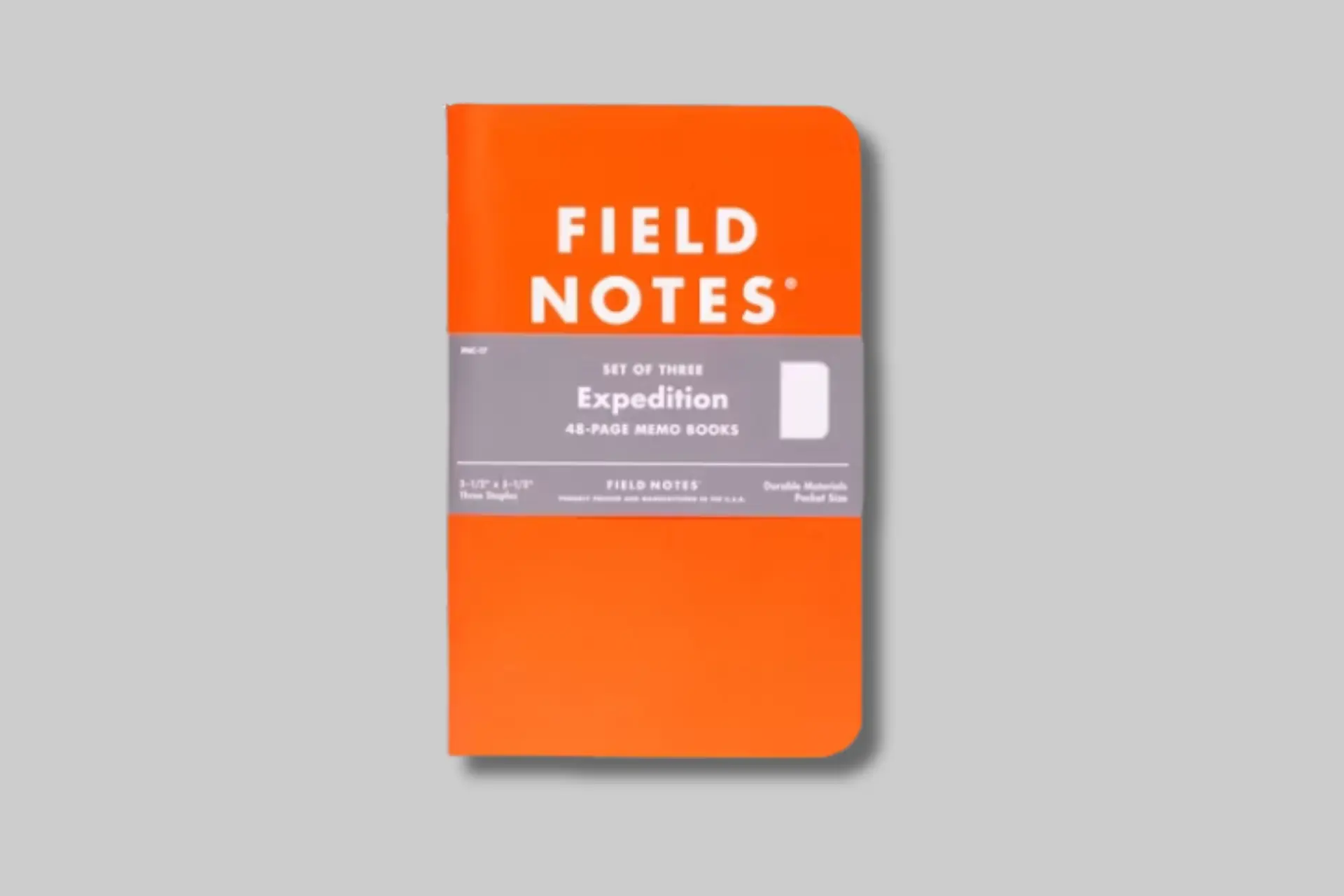 A stack of Field Notes Expedition notebooks with orange and black covers, featuring a topographic map design, in an outdoor setting. - Product Review