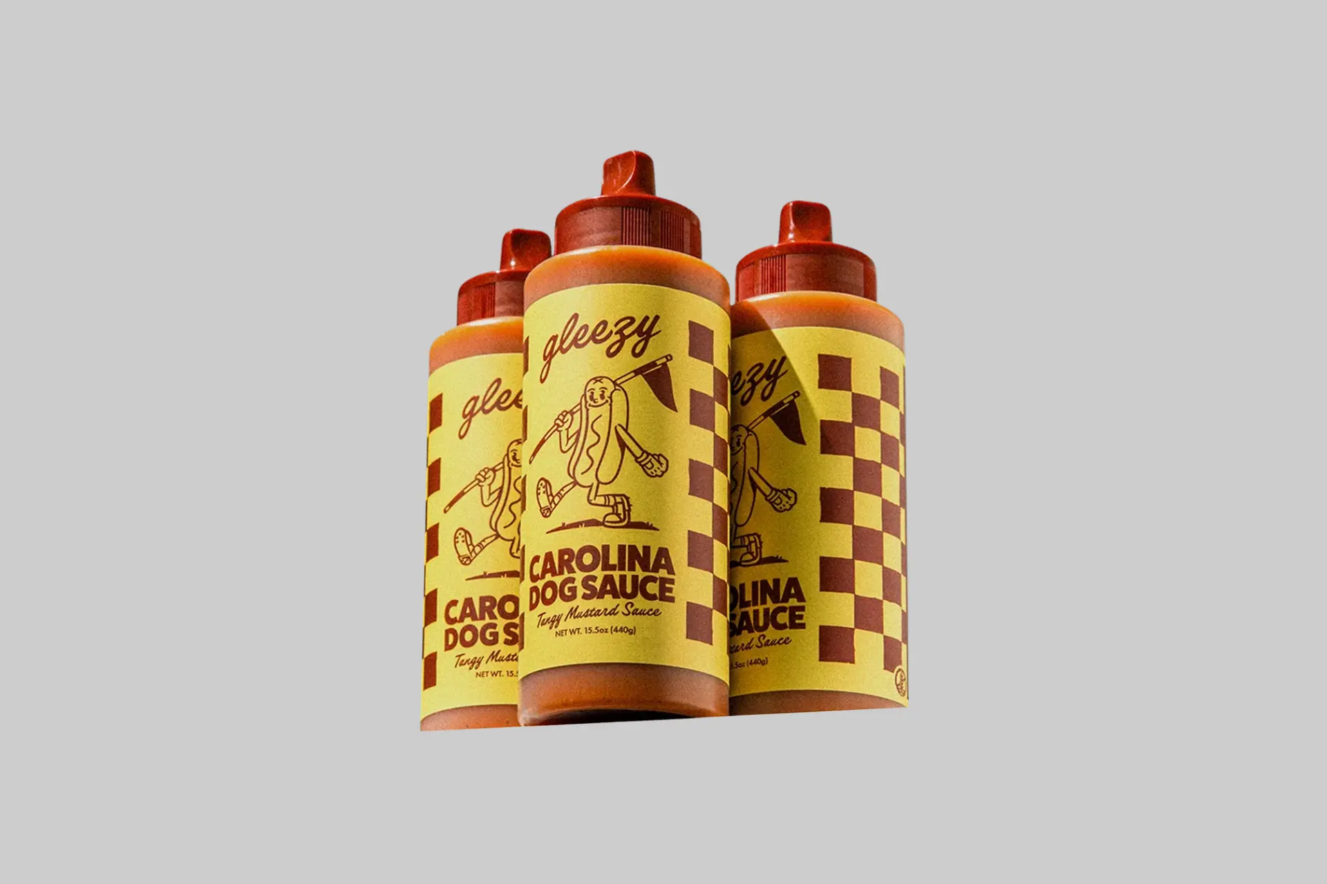 Three bottles of Gleezy Carolina Dog Sauce in tangy mustard yellow packaging against a blue background, showing the 15.5 fl oz bottle and brand logo.