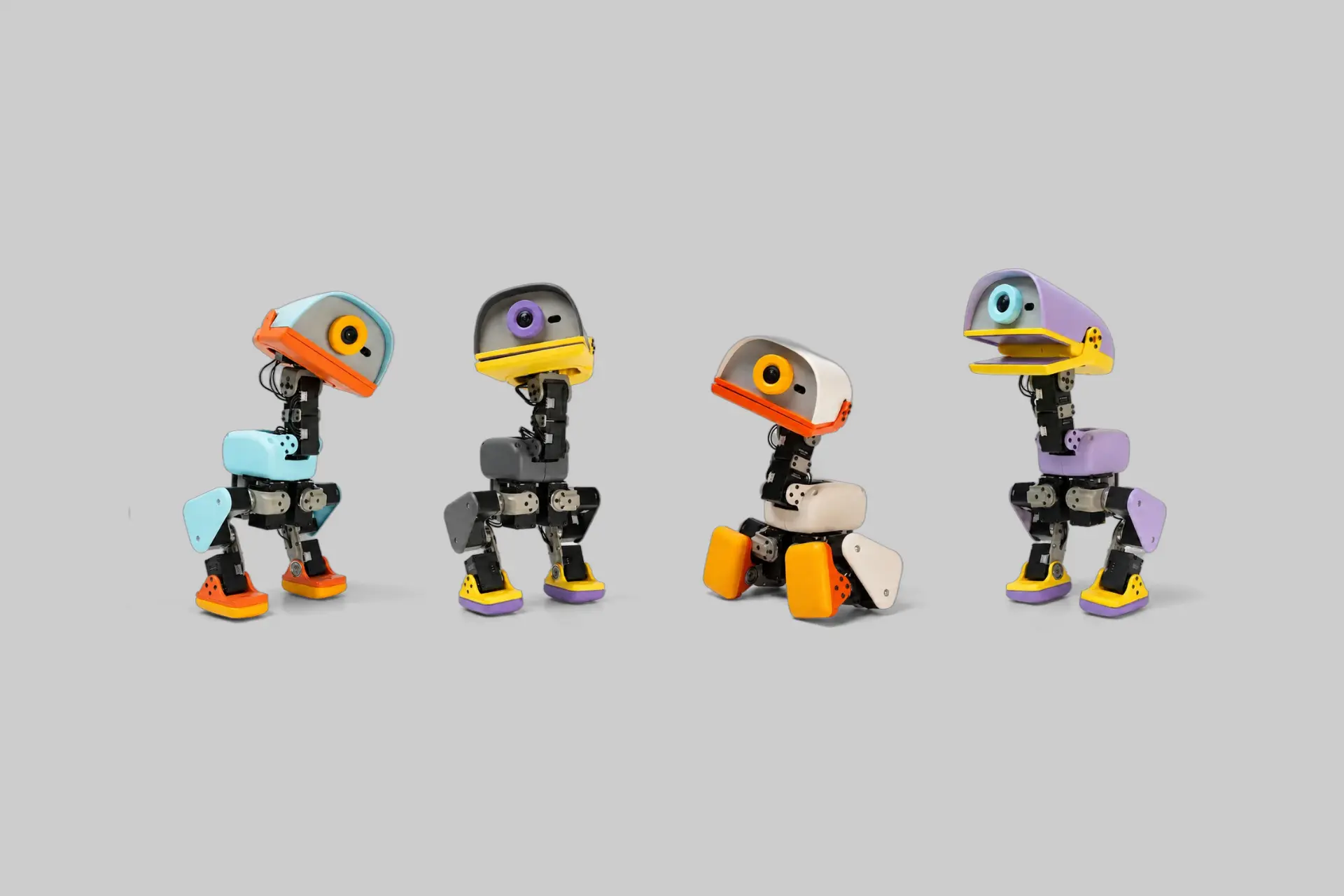 The four Microduck colorways, Cream, Graphite, Lavender, and Sky, standing side by side, showing the 25cm biped robot's beak, camera, and compact duck-inspired form factor.