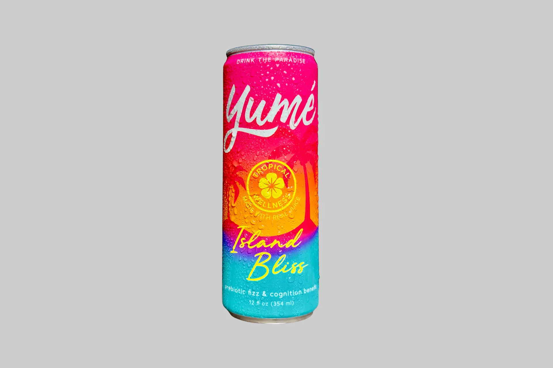 A can of Yumé Island Bliss sparkling adaptogen drink against a tropical background, showing its mango and passionfruit-forward tropical label design with the Yumé logo.