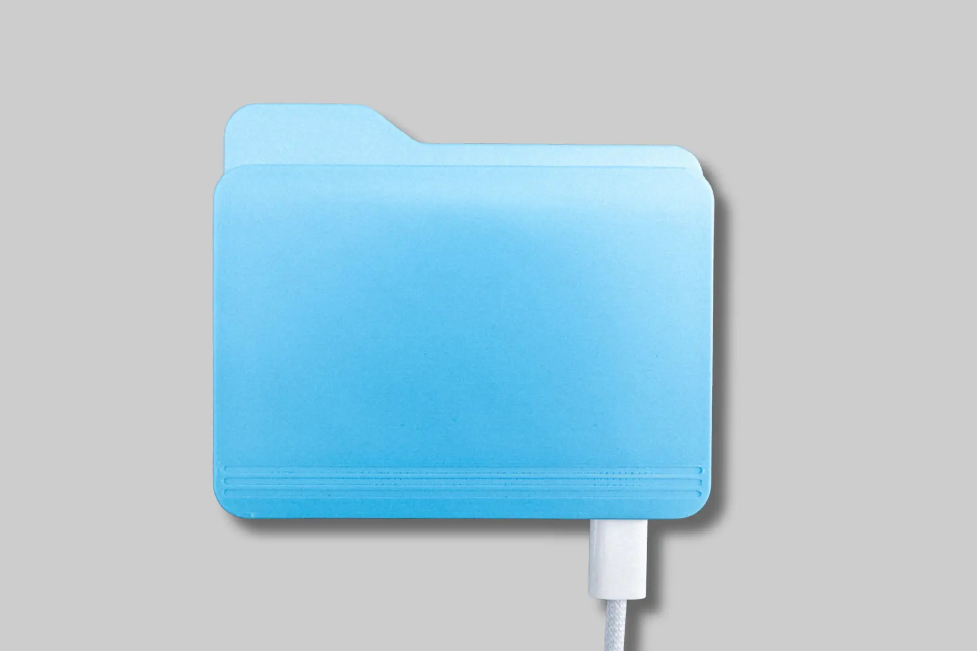 A Super Fantastic Toys Folderdrive, a blue external USB-C drive shaped like the classic macOS folder icon, next to a laptop. - Product Review